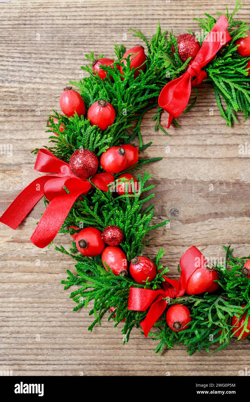 Couronne de porte de Noël traditionnel avec des brindilles et thuja vert rose fruits sauvages. Décoration de fête Banque D'Images