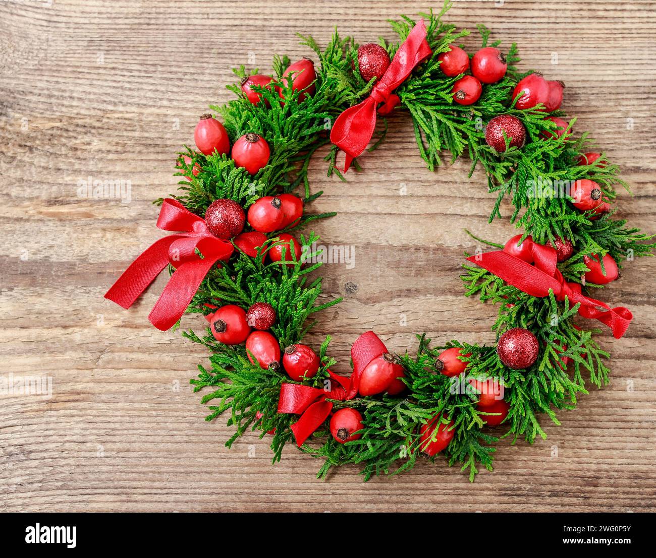 Couronne de porte de Noël traditionnel avec des brindilles et thuja vert rose fruits sauvages. Décoration de fête Banque D'Images