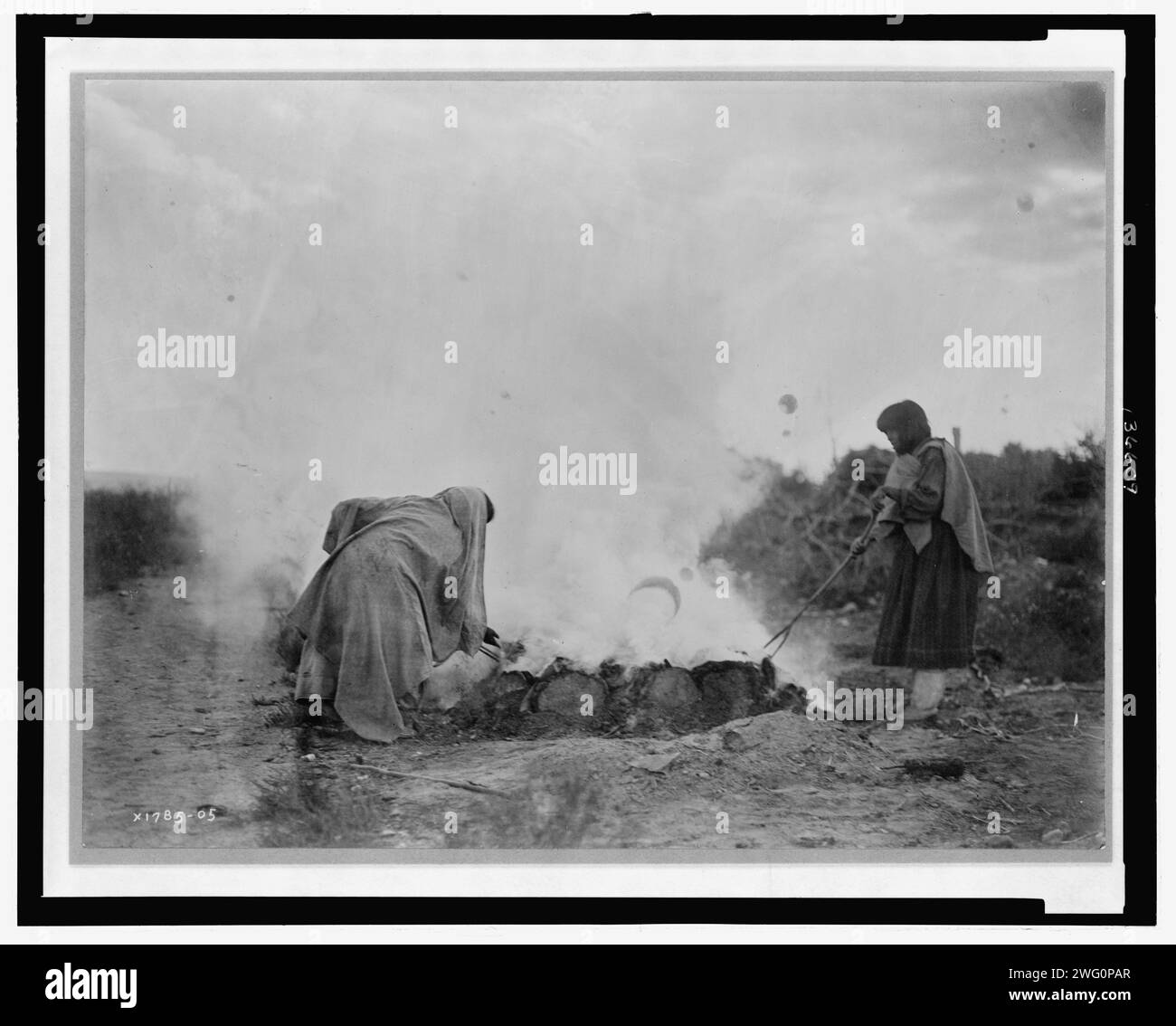 Brûleurs de poterie à Santa Clara, c1905. La photographie montre deux femmes, probablement Tewa, qui s'occupent d'un foyer à Santa Clara Pueblo, Nouveau-Mexique. Banque D'Images