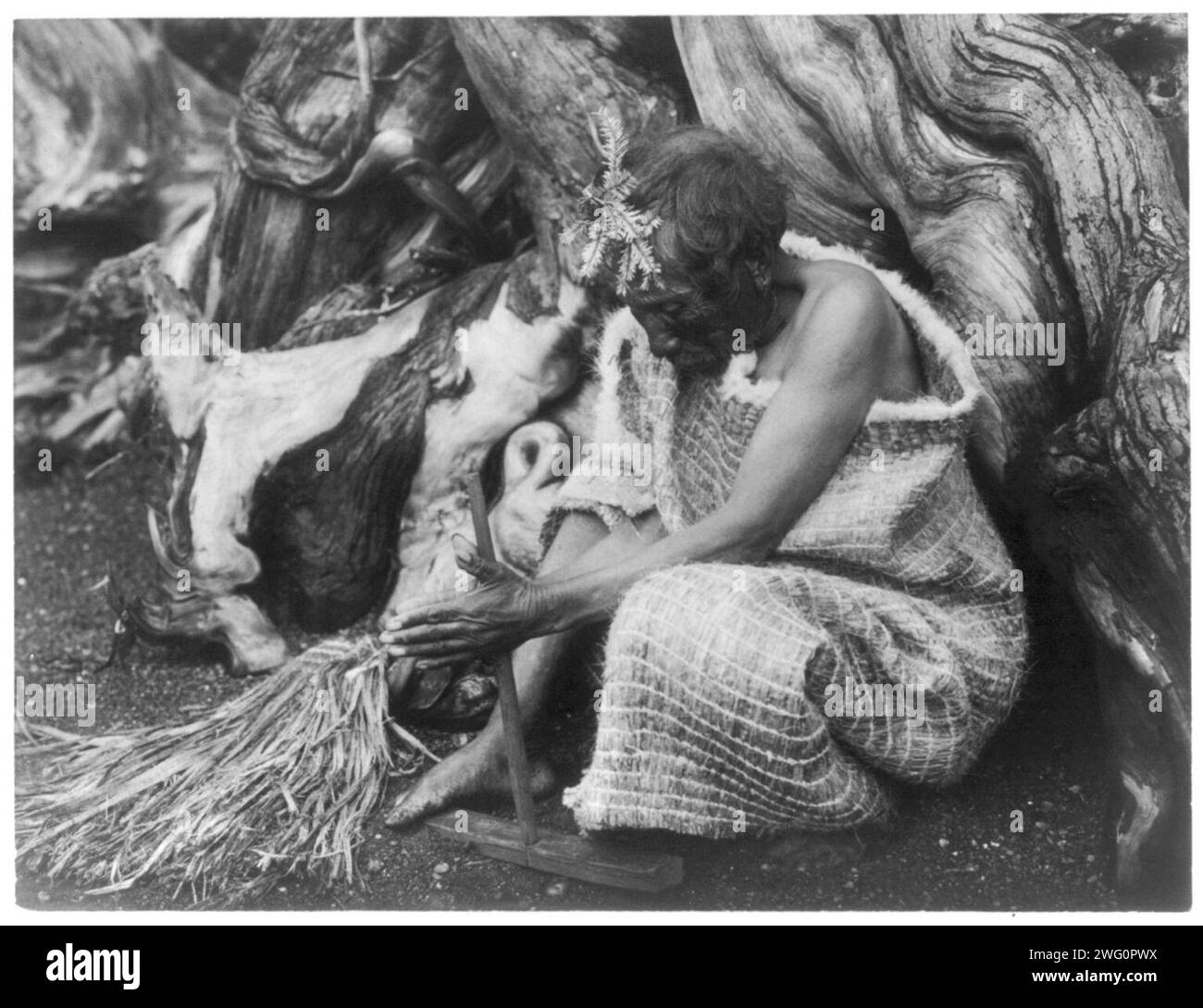 L'exercice d'incendie-Koskimo, c1914. Homme de Koskimo, portrait en pied, assis sur le sol, face vers le bas, à l'aide d'un exercice d'incendie. Banque D'Images