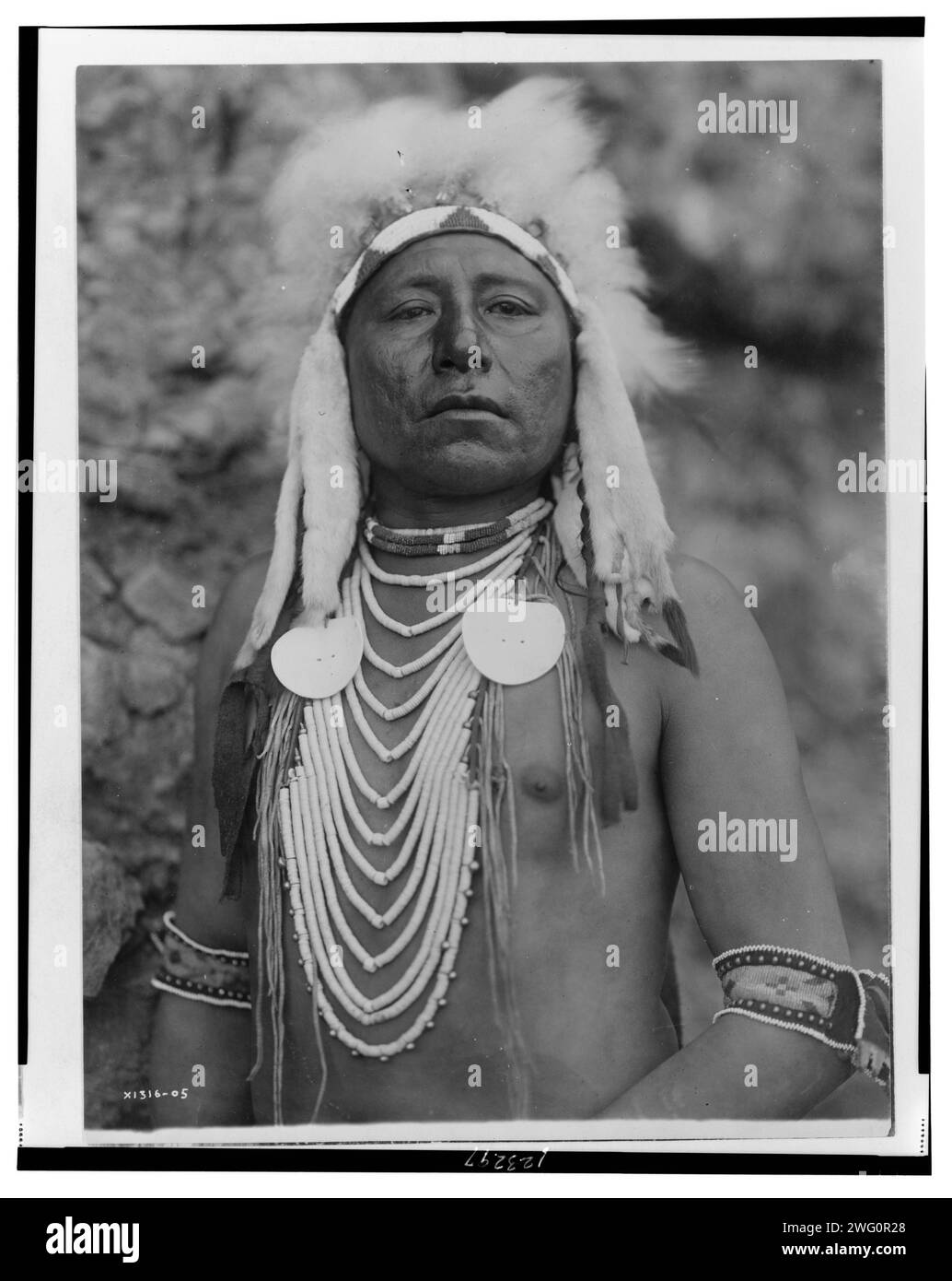 Dans quel sens, c1905. Crow Indian, portrait mi-long, face à l'avant, coiffé et plusieurs colliers. Banque D'Images Dans quel sens, c1905. Crow Indian, portrait mi-long, face à l'avant, coiffé et plusieurs colliers. Banque D'Images