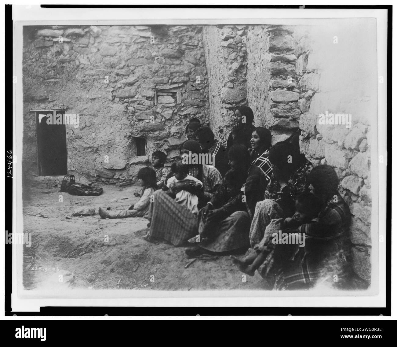 Vie Hopi, c1907. Plusieurs femmes et enfants Hopi assis sur le sol de la structure intérieure non meublée. Banque D'Images