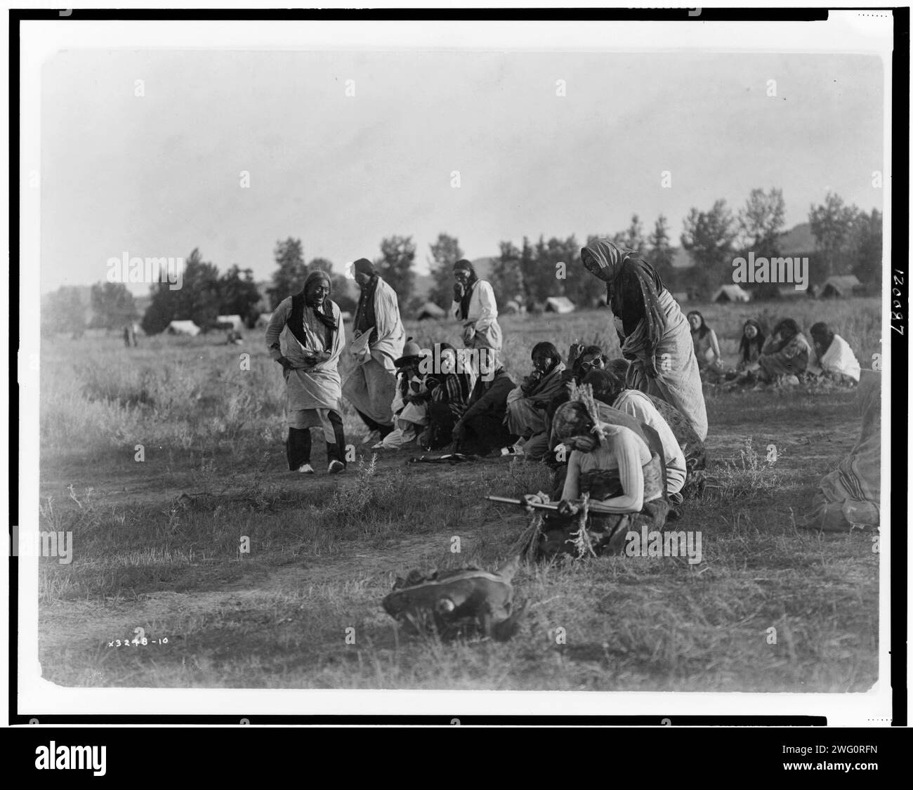 Prêtres passant devant la pipe-Cheyenne, c1910. Groupe de Cheyennes, la plupart assis dans un demi-cercle pendant la cérémonie de danse du soleil, femme au premier plan tient la pipe, crâne de buffle au premier plan. Banque D'Images