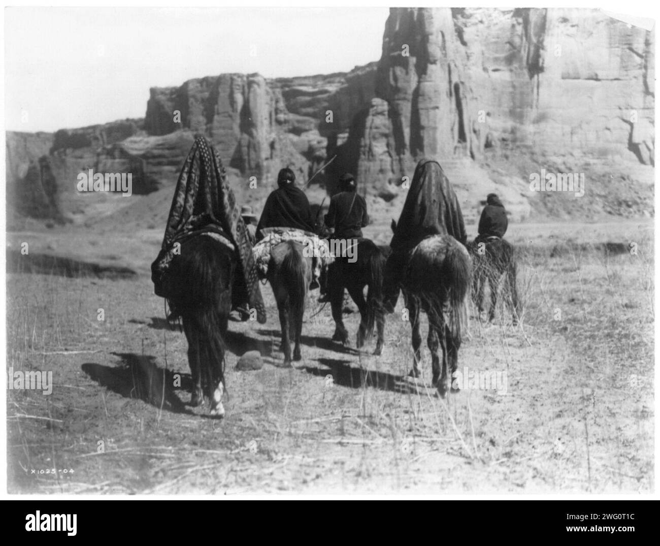 Marche à travers Tesacod Canyon, c1905. Vue arrière des Indiens Navajo à cheval faisant leur chemin sur le sol clairsemé, sec et herbeux du Canyon Tesacod. Banque D'Images