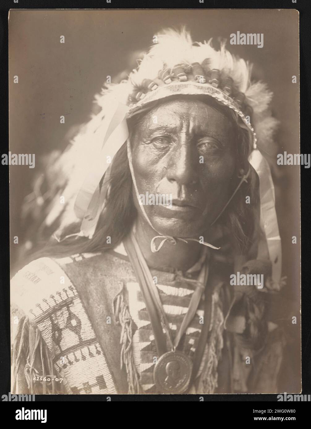 Jack Red Cloud, 1907. La photographie montre le portrait tête et épaules de Jack Red Cloud, debout, portant une coiffe complète, des vêtements traditionnels et un médaillon, face à l'avant. Banque D'Images