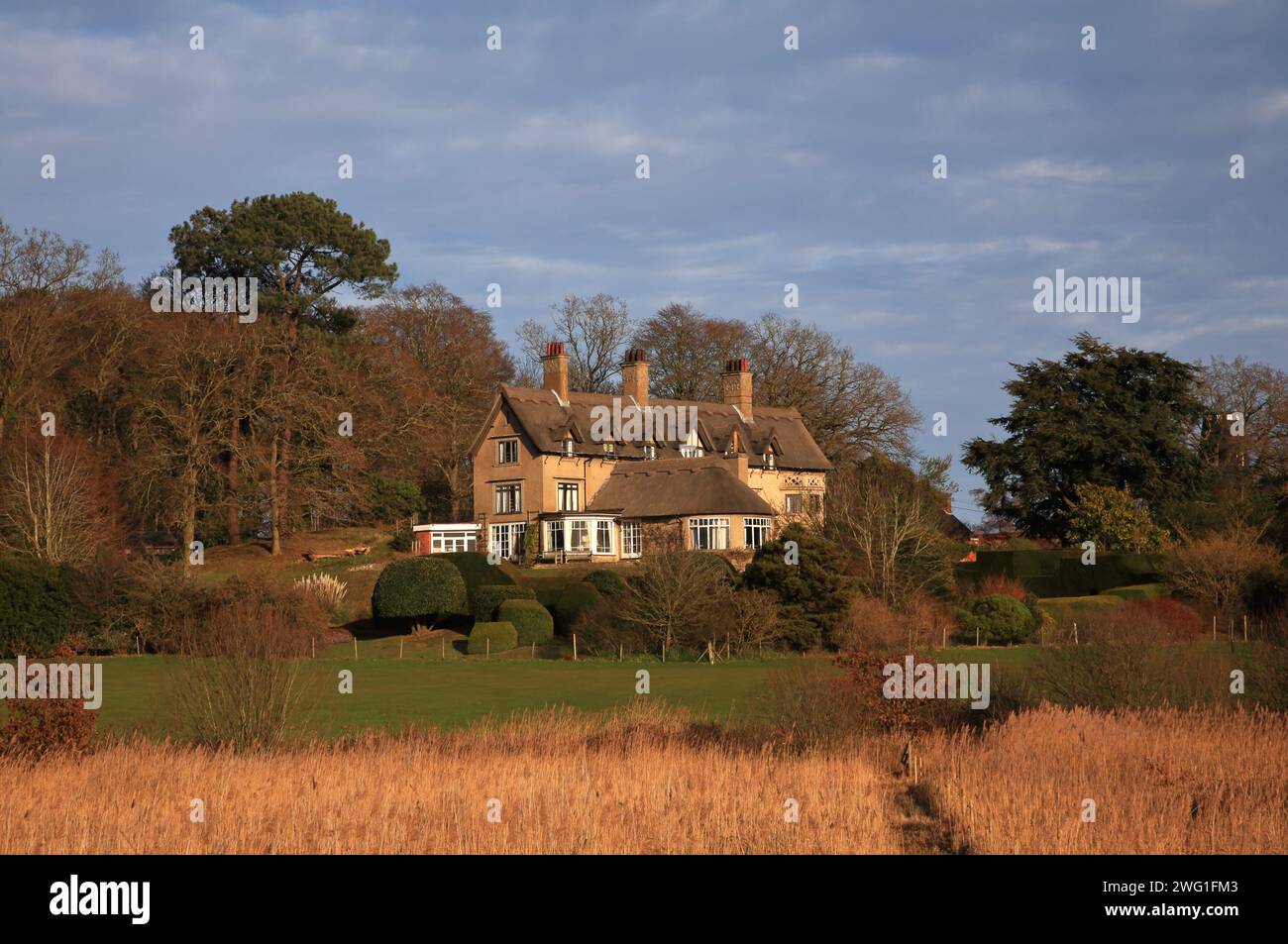 Une vue de How Hill House et des jardins depuis un sentier près de la rivière Ant sur les Norfolk Broads à Ludham, Norfolk, Angleterre, Royaume-Uni. Banque D'Images