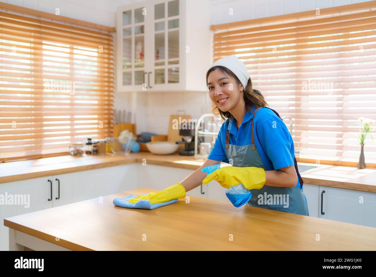 Femme de ménage comme elle nettoie diligemment et organise la cuisine à la maison une attention méticuleuse aux détails et le dévouement de l'équipe de nettoyage Banque D'Images