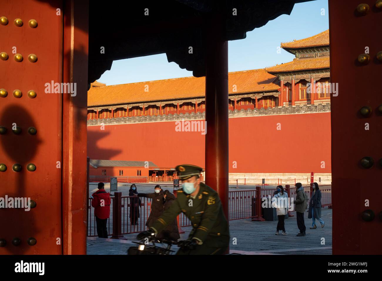 Un soldat de la police armé portant un masque sort d'une porte à vélo dans la Cité interdite à Pékin, en Chine. 02 janvier 2022 Banque D'Images