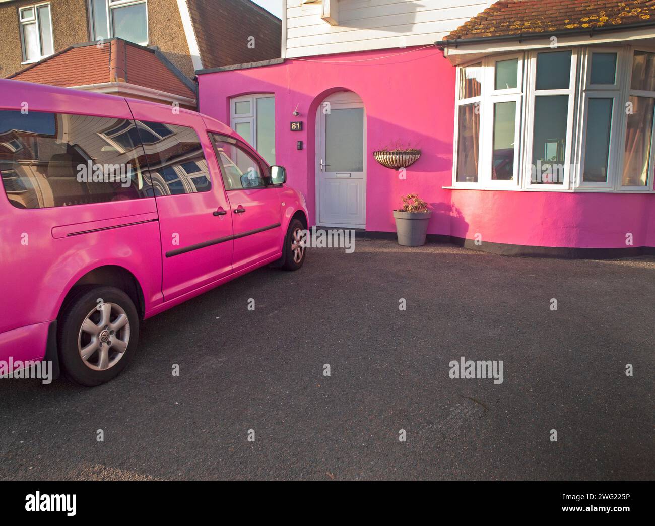 Une voiture rose garée devant une maison rose Banque D'Images