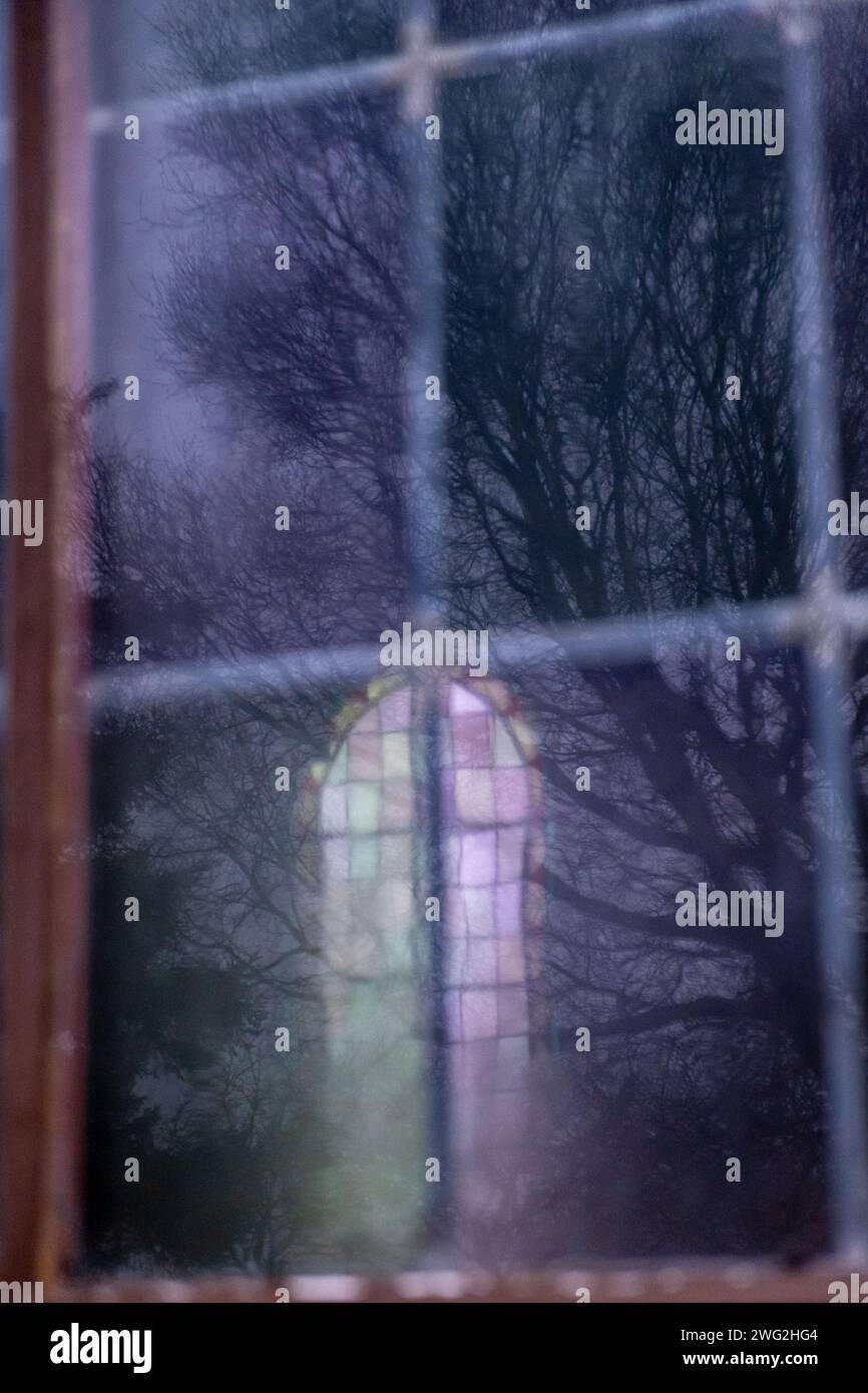 Climat hivernal Moody, arbres reflétés dans une fenêtre d'église en vitrail sur la côte norvégienne Banque D'Images