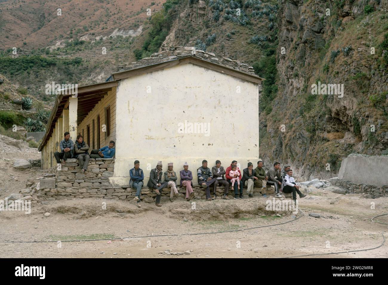 Un grand groupe d'hommes népalais assis près d'un bâtiment dans un village rural de Palata, district de Dolpa, Népal occidental, 2023. Banque D'Images