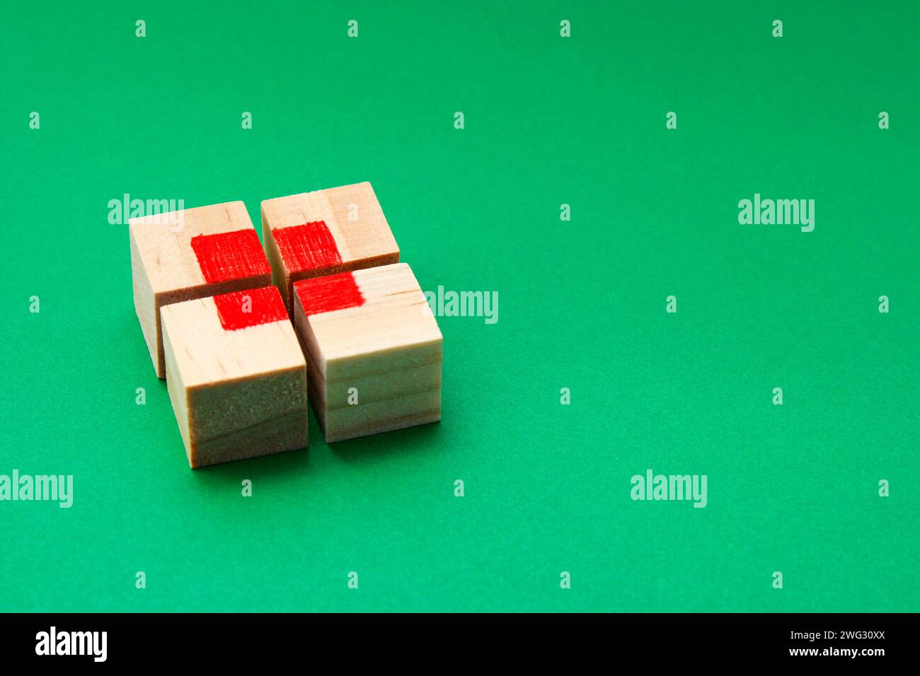 Puzzle cube en bois formant un carré rouge en son centre avec un fond vert Banque D'Images