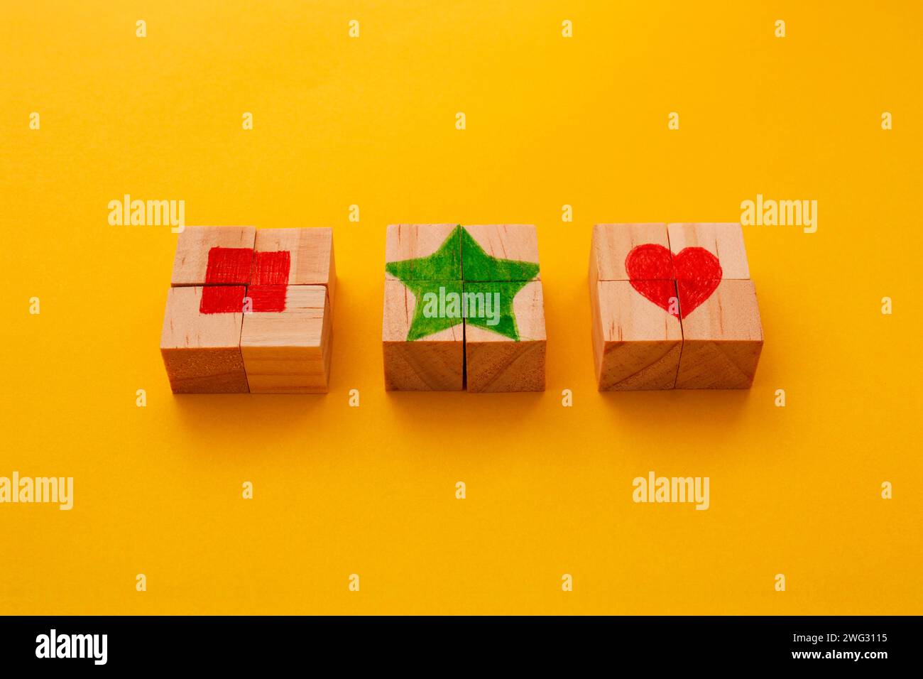 Trois cubes de puzzle en bois formant un carré, une étoile et un coeur en son centre Banque D'Images