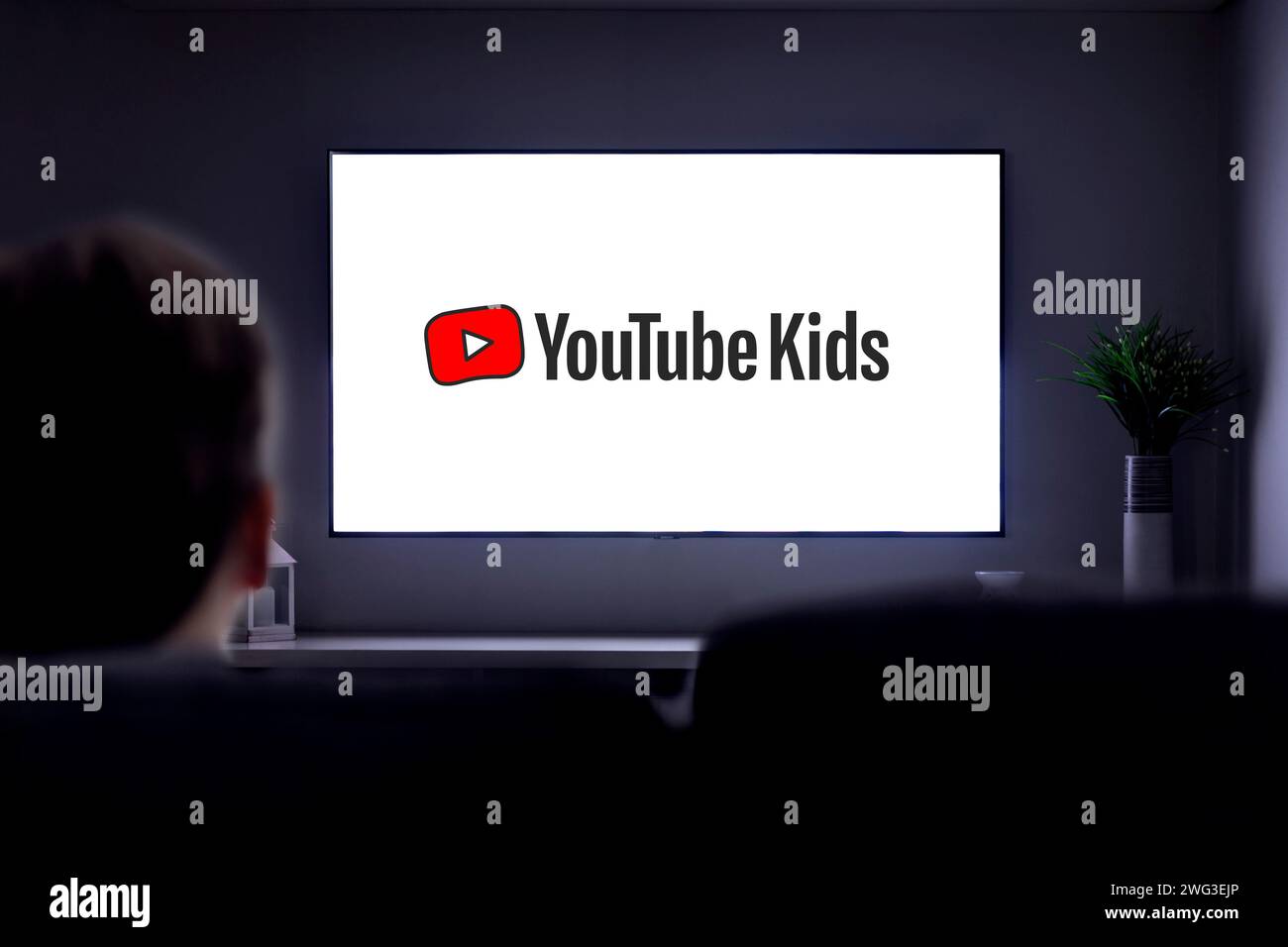 YouTube Kids à la télévision. Un petit garçon seul sur le canapé regardant une télévision intelligente avec le logo You tube Kids sur l'écran. Banque D'Images