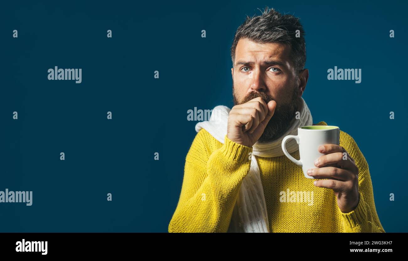 Homme barbu malade avec la grippe ou la fièvre tousser et boire du thé de guérison. Homme malsain toussant dans le poing. Homme malade en pull enveloppé dans une écharpe avec une tasse Banque D'Images