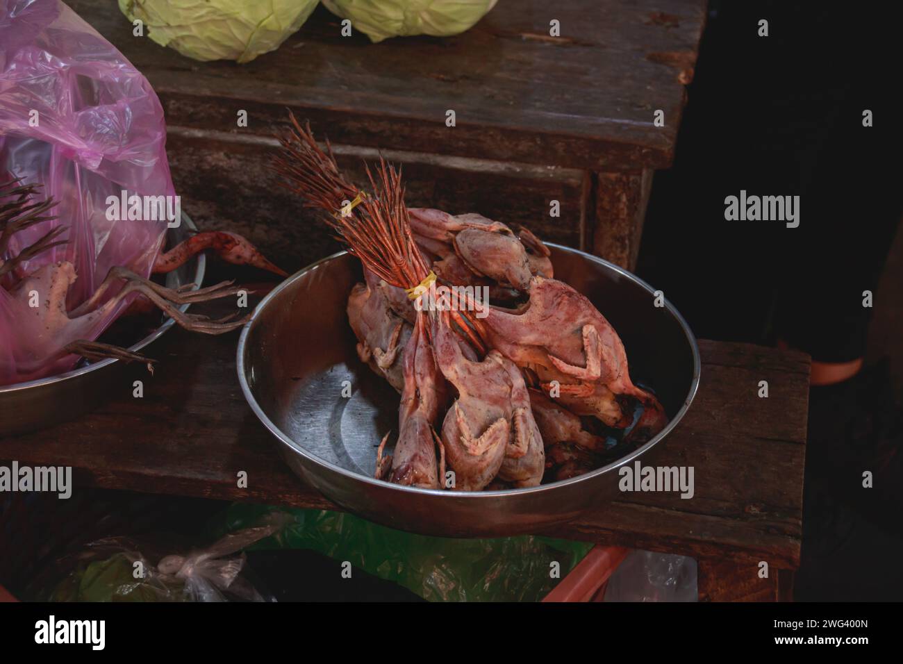 Viande de volaille indigène crue disposée dans un bol en métal sur un marché local montrant la vie quotidienne, la tradition et la culture khmère franche à Kampot, au Cambodge Banque D'Images