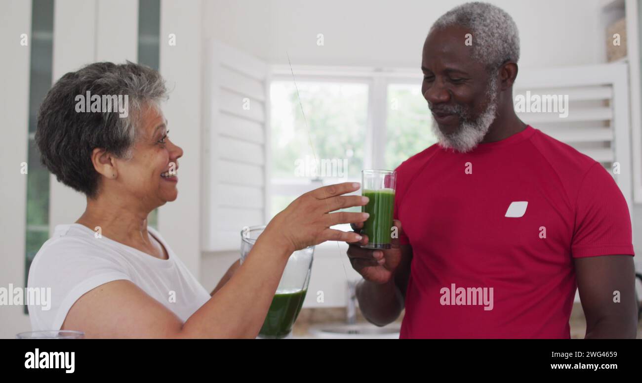 Femme biraciale et homme afro-américain partagent une boisson saine à la maison Banque D'Images