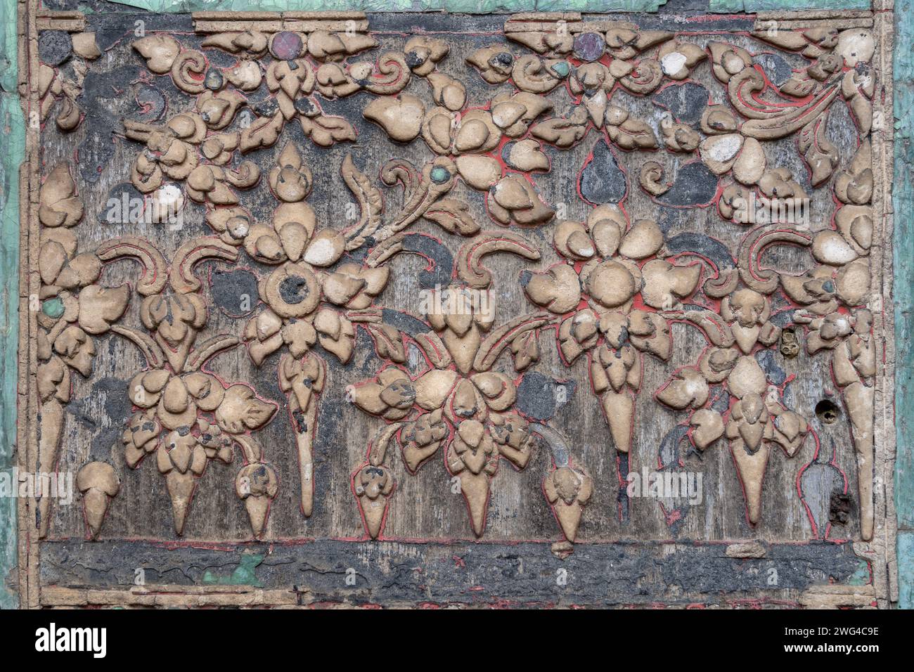 Détail de stuc ancien sur bois avec motif floral traditionnel Lanna Thai sur l'extérieur de la bibliothèque hor trai à Wat Duang Dee, Chiang mai, Thaïlande Banque D'Images