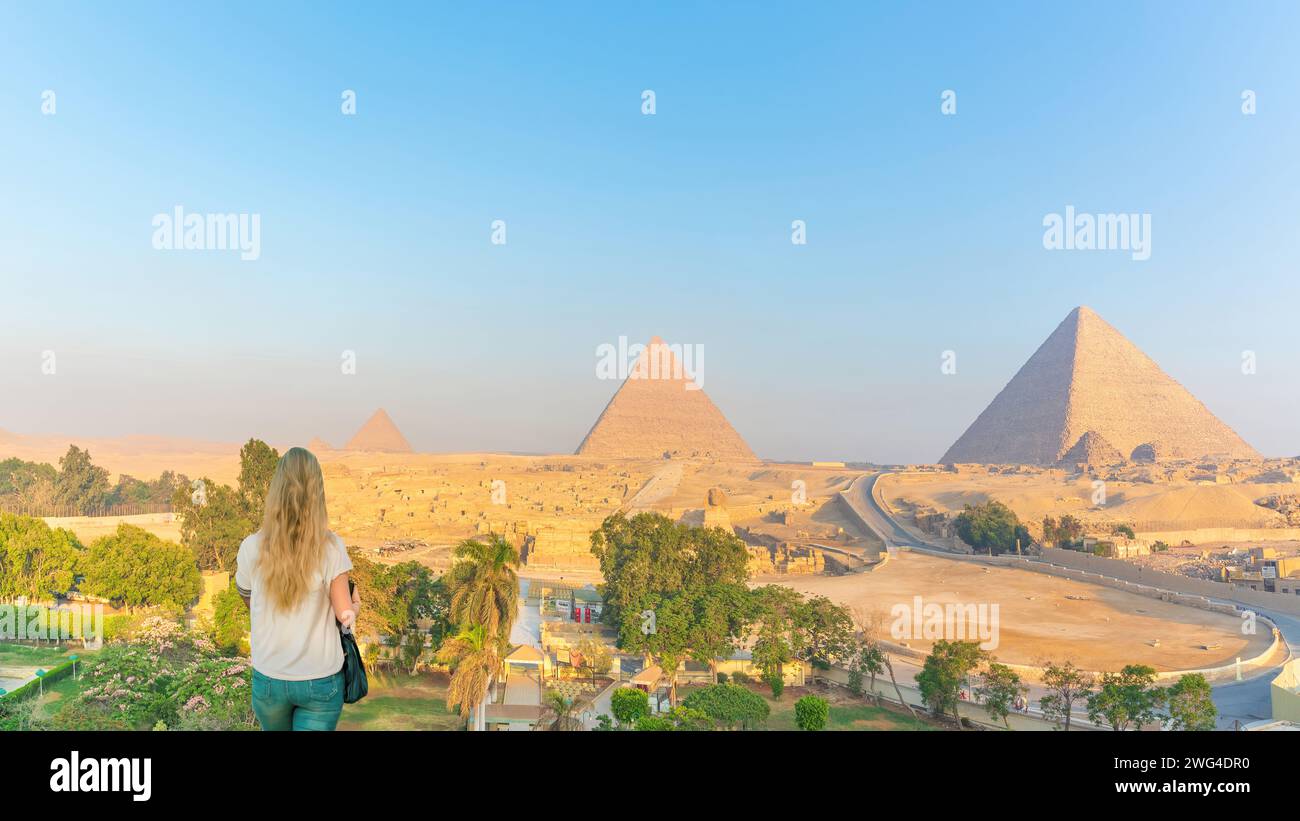 Gizeh, Egypte - Une femme aux cheveux blonds regarde les pyramides au lever du soleil à Gizeh, Egypte Banque D'Images