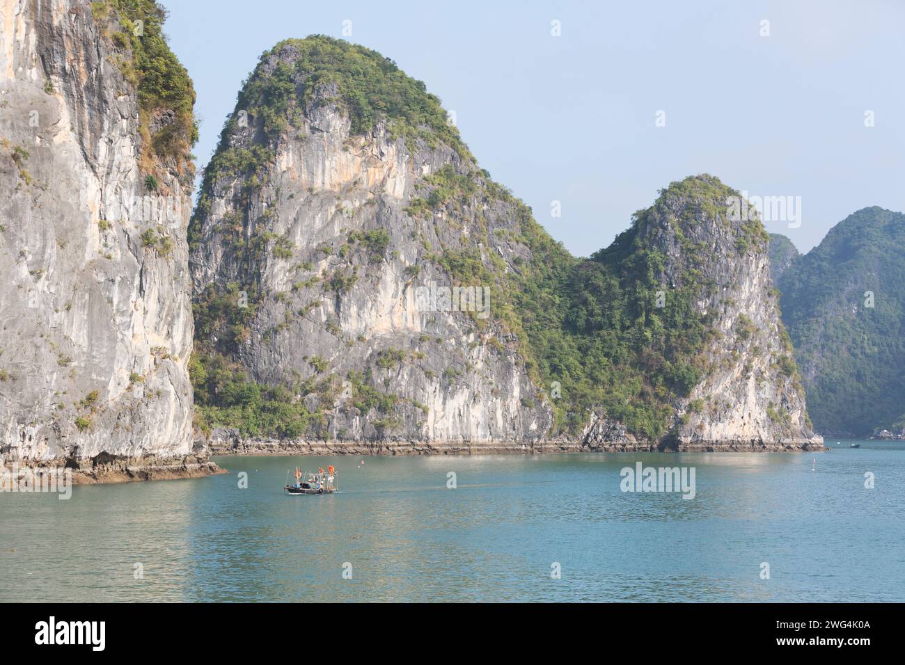 Vietnam, baie d'Halong, bateau de pêche local, donne un sens de proportion de la taille des karsts montagneux sont. Banque D'Images
