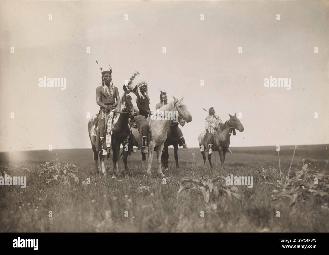 Le parti de guerre, 1905. La photographie montre un groupe d'Indiens Crow à cheval. Chef, au milieu, coiffé. Banque D'Images Le parti de guerre, 1905. La photographie montre un groupe d'Indiens Crow à cheval. Chef, au milieu, coiffé. Banque D'Images
