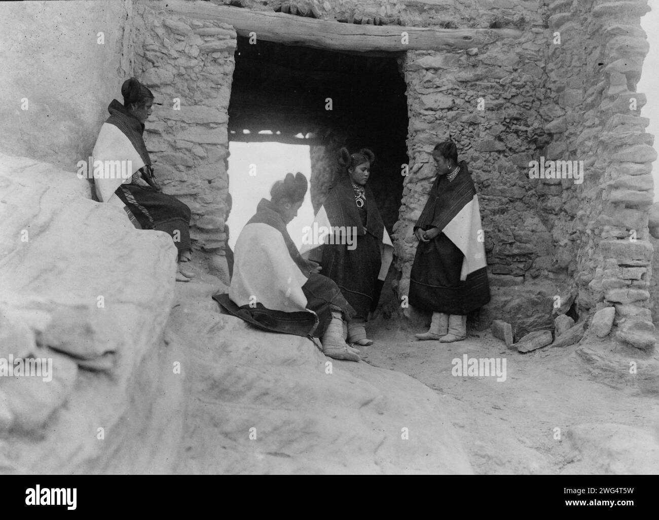 Jeunes filles modestes, c1906. Quatre jeunes femmes Hopi se rassemblent devant une entrée. Banque D'Images