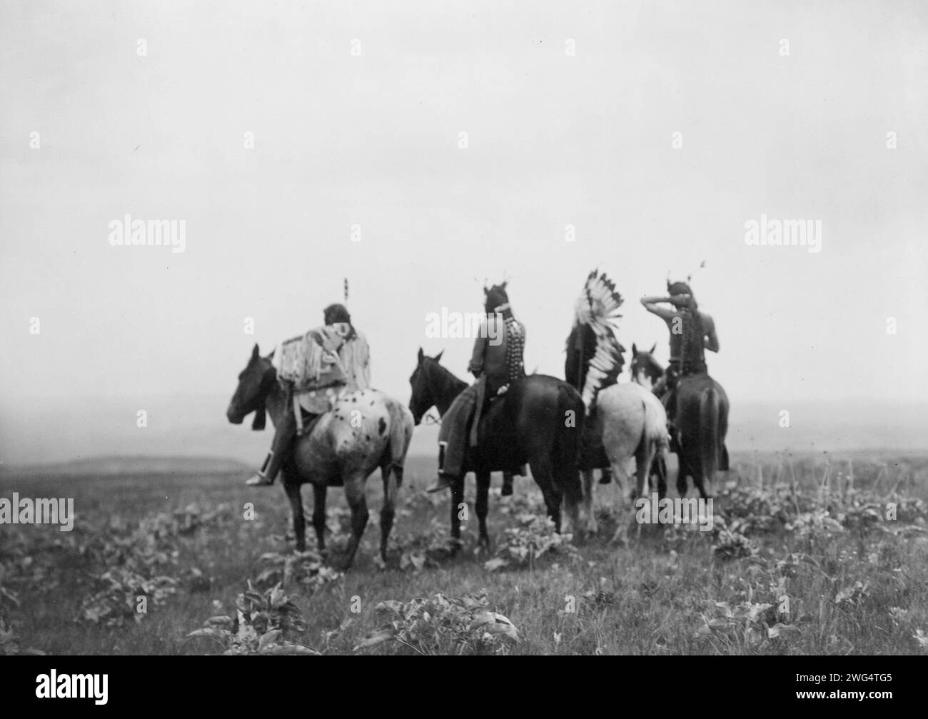 Absoraks, c1905. Vue arrière de quatre Indiens Crow, dont Shot in the Hand et Bull Chief, à cheval, Montana. Banque D'Images Absoraks, c1905. Vue arrière de quatre Indiens Crow, dont Shot in the Hand et Bull Chief, à cheval, Montana. Banque D'Images