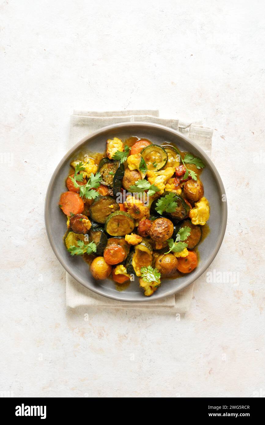 Ragoût végétarien avec légumes de saison mélangés sur une assiette sur fond clair avec espace de copie. Concept de consommation saine et confortable. Vue de dessus, pose à plat Banque D'Images