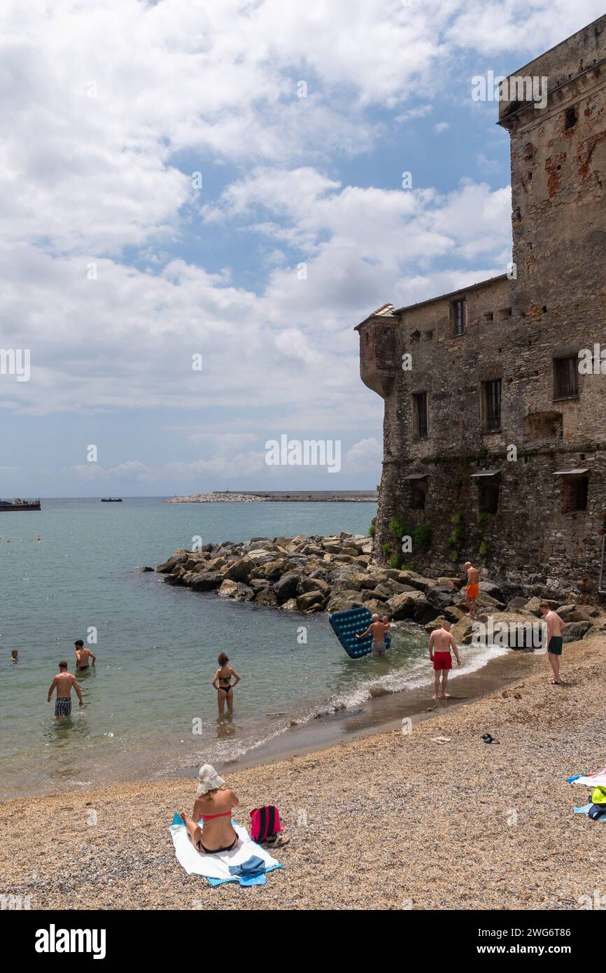 Les gens bronzent sur la petite plage du château de Rapallo, construit en 1551 pour défendre la ville des pirates sarrasins, Rapallo, Gênes, Ligurie, Italie Banque D'Images