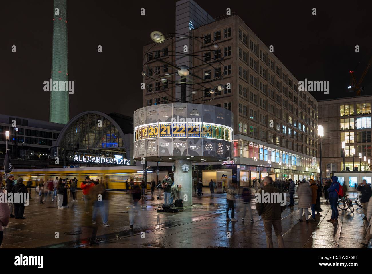 Die Weltzeituhr auf dem Alexanderplatz in Berlin ist ein beliebter Treffpunkt und Buehne fuer Kuenstler. 03.02.2024, Berlin, GER - Die Weltzeituhr auf dem Alexanderplatz. Abendstimmung mit Passanten und Musiker., Berlin Berlin Deutschland Alexanderplatz, Weltzeituhr *** l'horloge mondiale sur Alexanderplatz à Berlin est un lieu de rencontre populaire pour les artistes 03 02 2024, Berlin, GER l'horloge mondiale sur Alexanderplatz ambiance nocturne avec passants et musiciens, Berlin Berlin Allemagne Alexanderplatz, horloge mondiale Banque D'Images