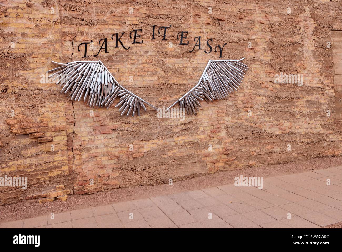 Art tubulaire en métal sur mur de briques pour les touristes à poser pour des photos à Standin' on the Corner Park dans le centre-ville de Winslow, Arizona Banque D'Images
