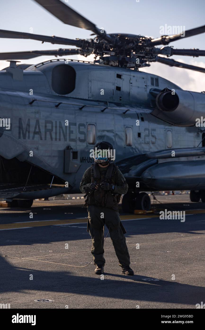 Le Sgt. Cody Kimbley, observateur aérien du Marine corps 265 (rein), 31st Marine Expeditionary Unit, se prépare à charger des Marines dans un CH-53E Super Stallion avant un exercice de raid hélicoptère sur le navire d'assaut amphibie USS America (LHA 6) en mer des Philippines, le 2 février, 2024. L'exercice simulait la prise de contrôle d'un aérodrome ennemi et le soutien d'autres opérations de déni. Le 31e MEU opère à bord des navires du USS America Amphibious Ready Group dans la zone d'opérations de la 7e flotte afin d'améliorer l'interopérabilité avec les alliés et les partenaires et de servir en tant que Banque D'Images