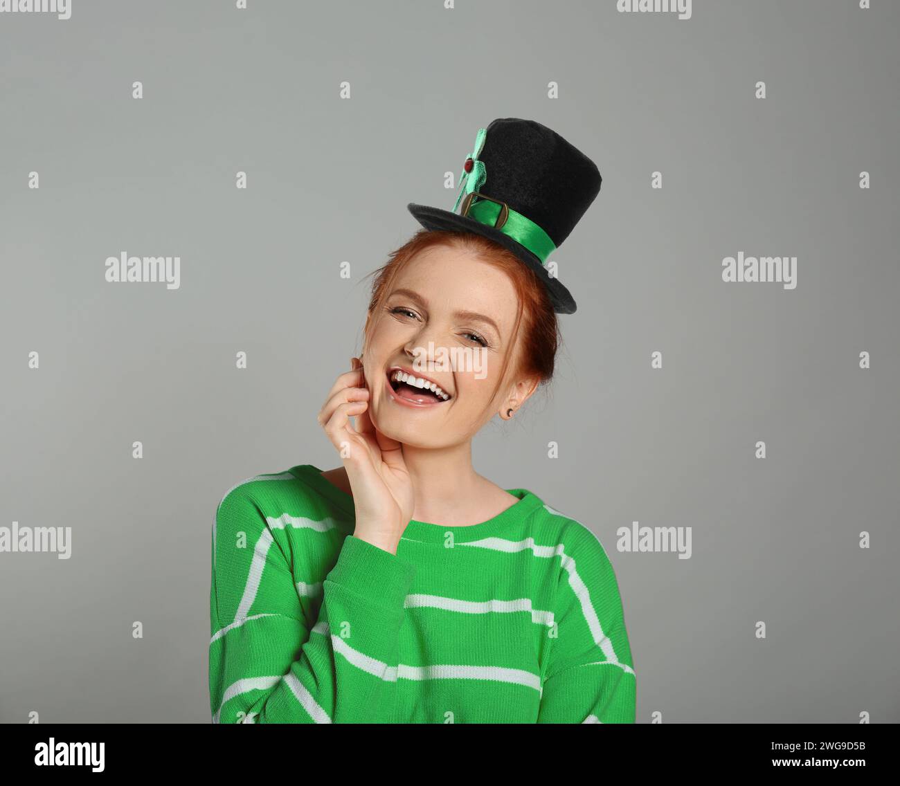 Prog Fête de Patrick. Jolie femme en chapeau de leprechaun sur fond gris Banque D'Images