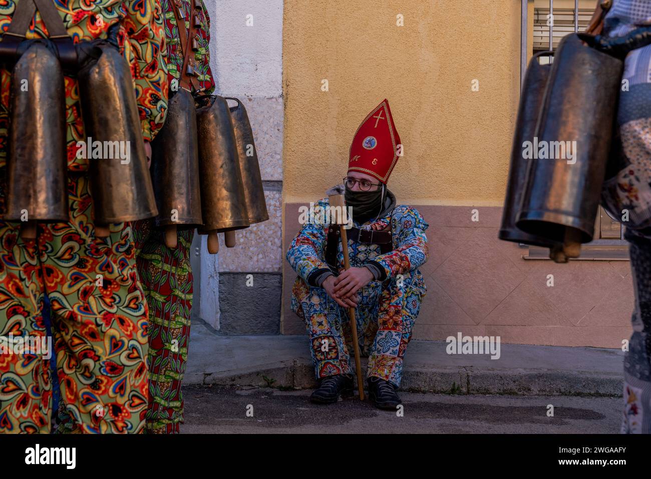 Un membre de la confrérie 'Endiablada' attend la procession de la sainte pendant la fête traditionnelle 'Endiablada'. Chaque année, du 2 au 3 février, la ville d'Almonacid del Marquesado dans le centre de l'Espagne accueille les festivités animées 'Endiablada' (la Fraternité des Diables), une tradition datant de l'époque médiévale ou plus tôt en l'honneur de la Candelaria et San Blas. Au cours de cet événement animé, les participants masculins arborent une tenue diabolique, notamment des costumes de combinaison éclatants et des chapeaux d'onglet rouges. Ornés de cloches en cuivre de taille importante autour de leur taille, les festivités se déroulent à mesure qu'ils traversent le méandre de la ville Banque D'Images