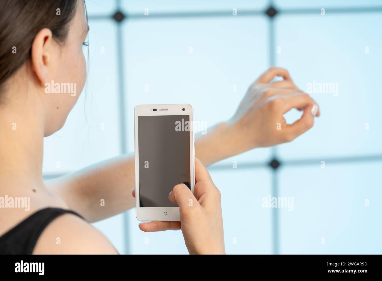 jeune femme utilisant l'application de téléphone portable pour vérifier les grains de beauté et autres imperfections de la peau pour le danger de pathologie Banque D'Images