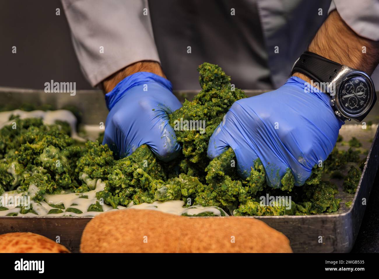 Baker mains pétrissant la pâte de sucre de pistache pour baklava frais, un dessert turc traditionnel dans une pâtisserie locale, Istanbul, Turquie Banque D'Images