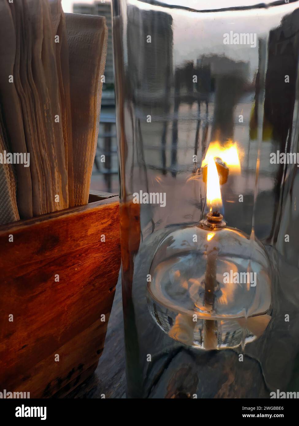 Lampe de bureau lanterne à huile, verre transparent, lumière romantique sur la table en bois, restaurant d'ambiance chaleureuse, gros plan, table à manger avec papier de soie Banque D'Images