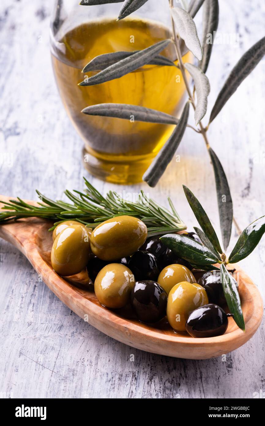 au premier plan un bol en bois avec des olives mélangées aromatisées au romarin et à l'huile d'olive extra vierge Banque D'Images