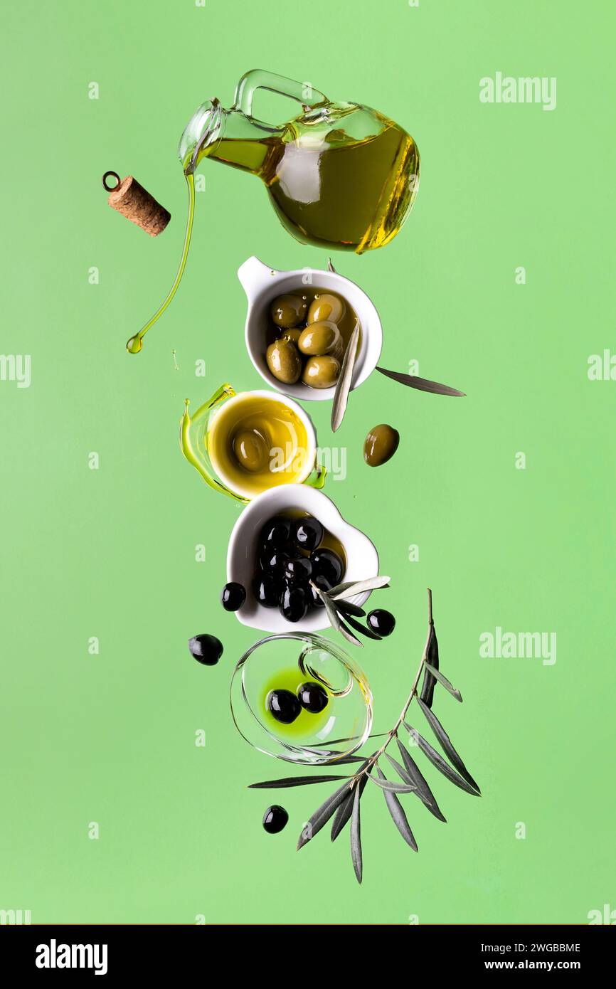 huile d'olive extra vierge et olives, composition en équilibre, nature morte en mouvement. fond vert Banque D'Images