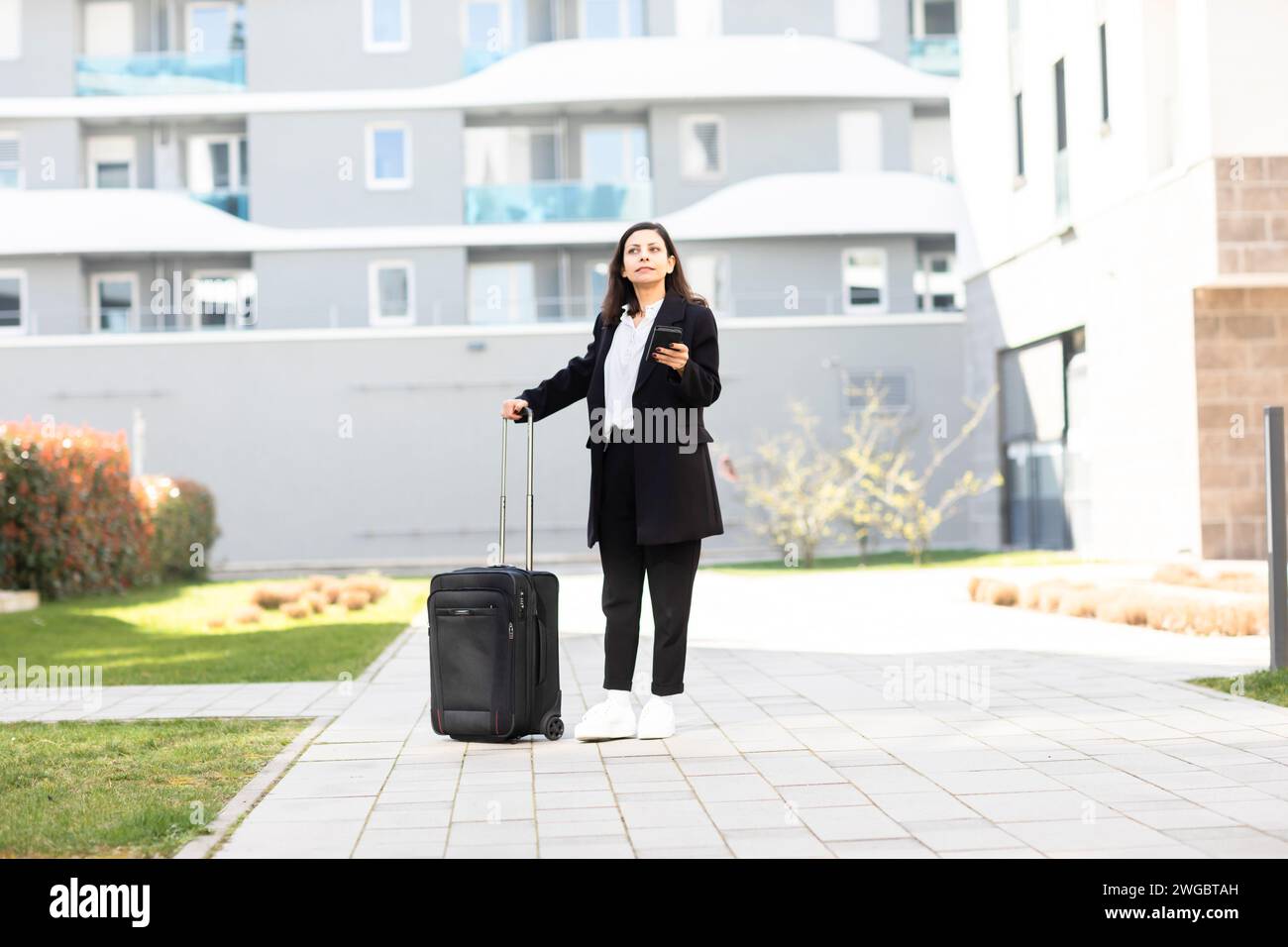 Femme debout devant un immeuble avec des bagages à roulettes, Allemagne Banque D'Images