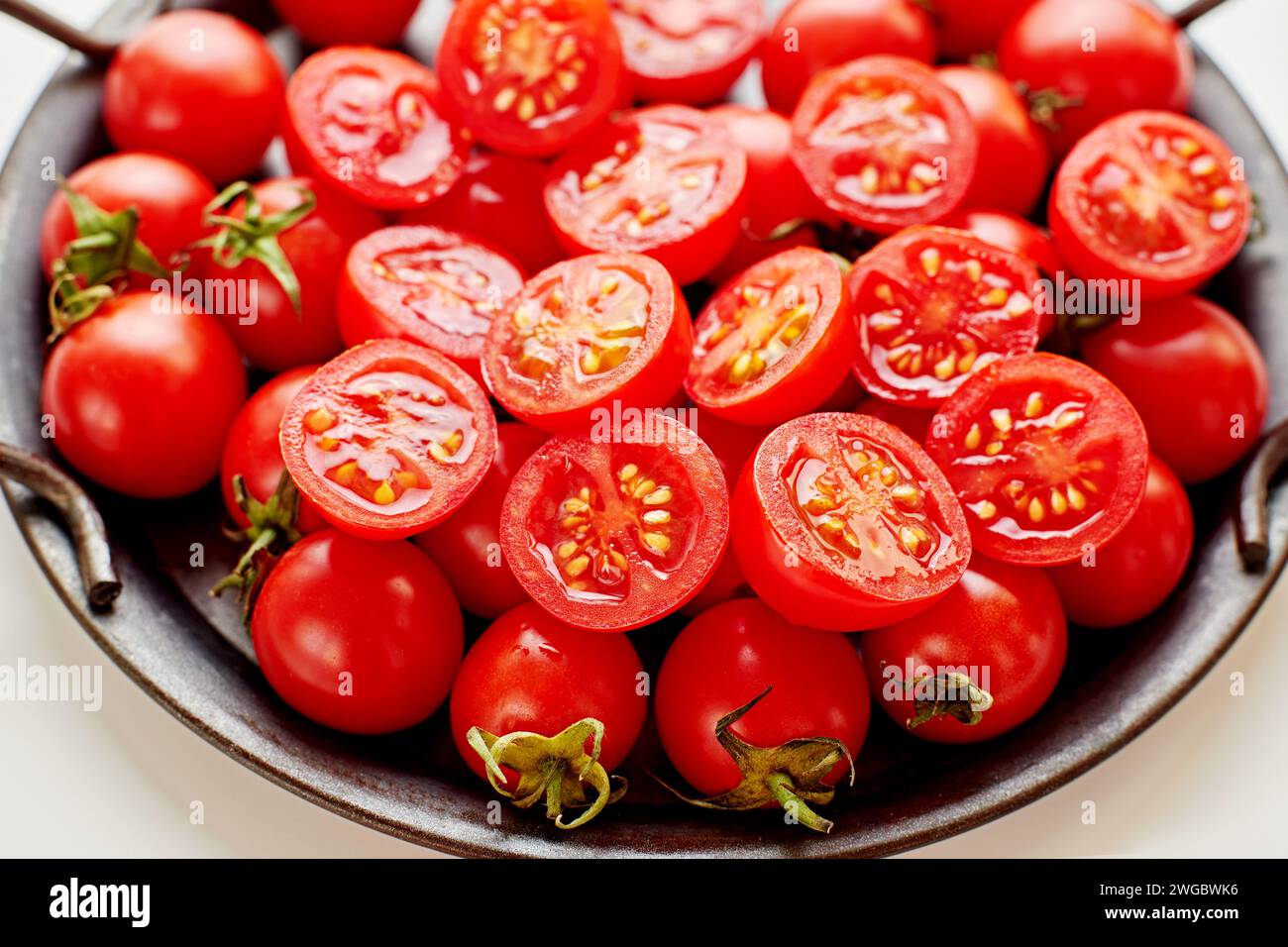 Gros plan d'une assiette de tomates cerises coupées en deux Banque D'Images