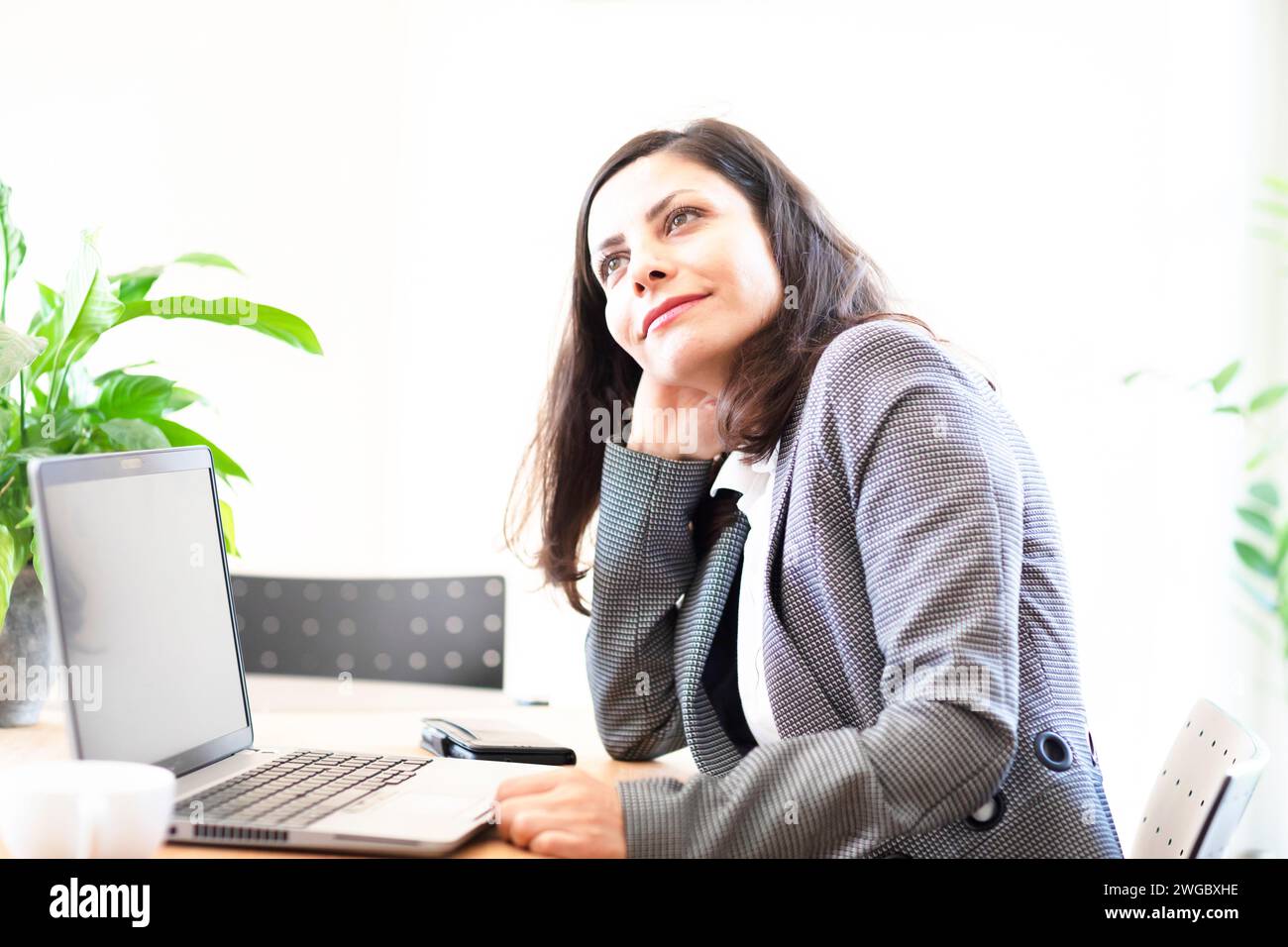Femme d'affaires assise dans un bureau devant un ordinateur portable Banque D'Images