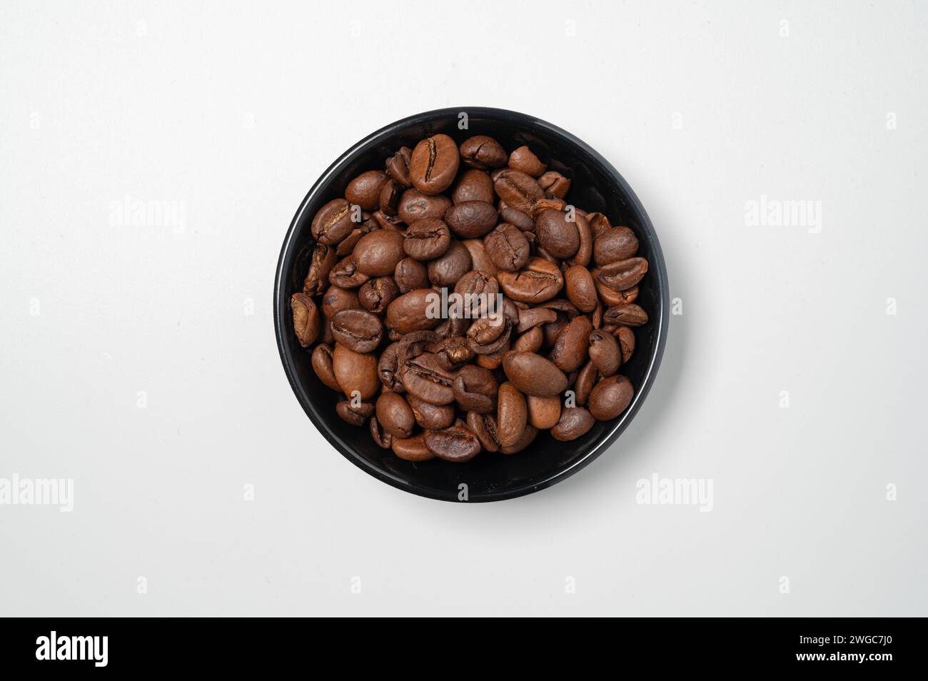 , Food, 04.02.2024, Minimalistische Komposition einer schwarzen Schüssel gefüllt mit gerösteten Kaffeebohnen, die auf einem hellen Untergrund steht, Banque D'Images