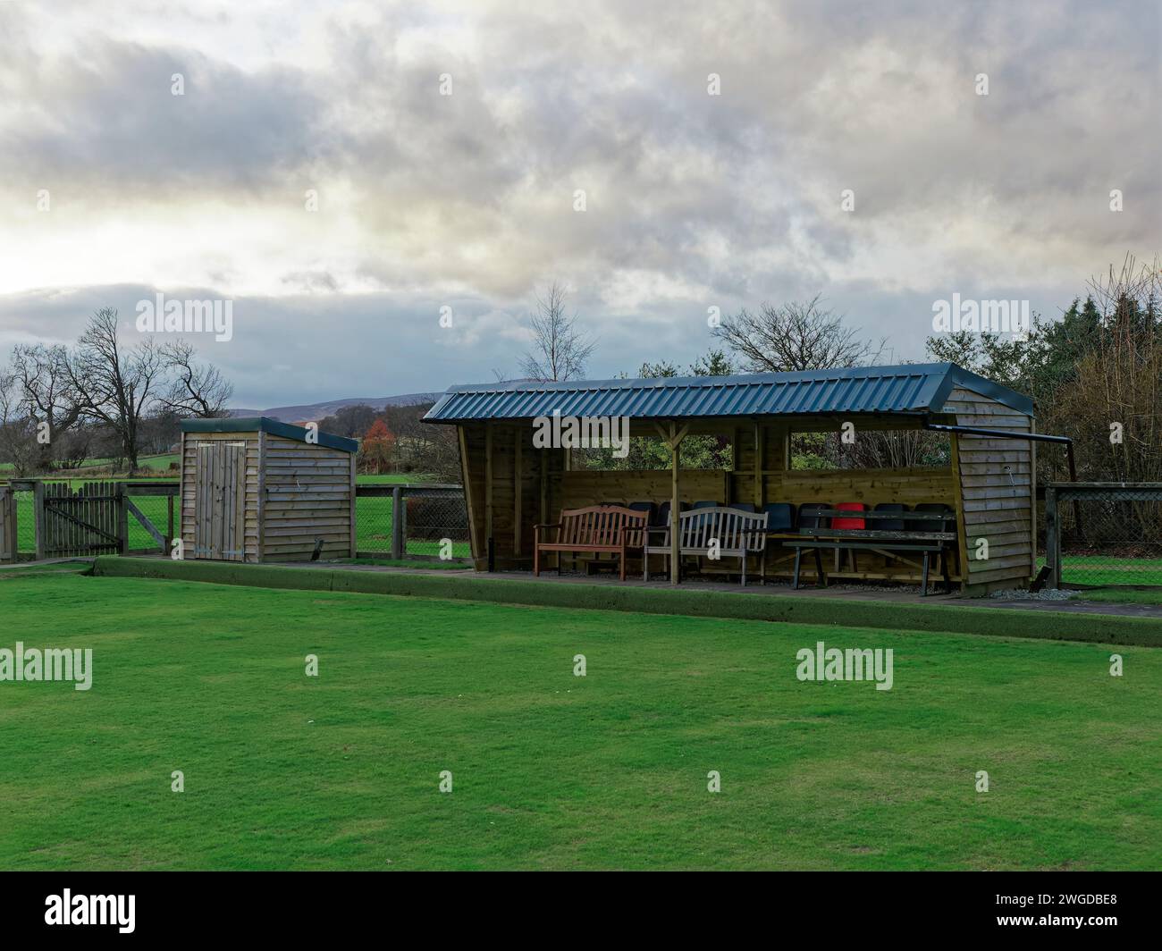 Le petit stand et le hangar en bois du Fettercairn Village Lawn Bowls Bowling Club, avec des chaises et des bancs rangés sous couvert à l'intérieur. Banque D'Images