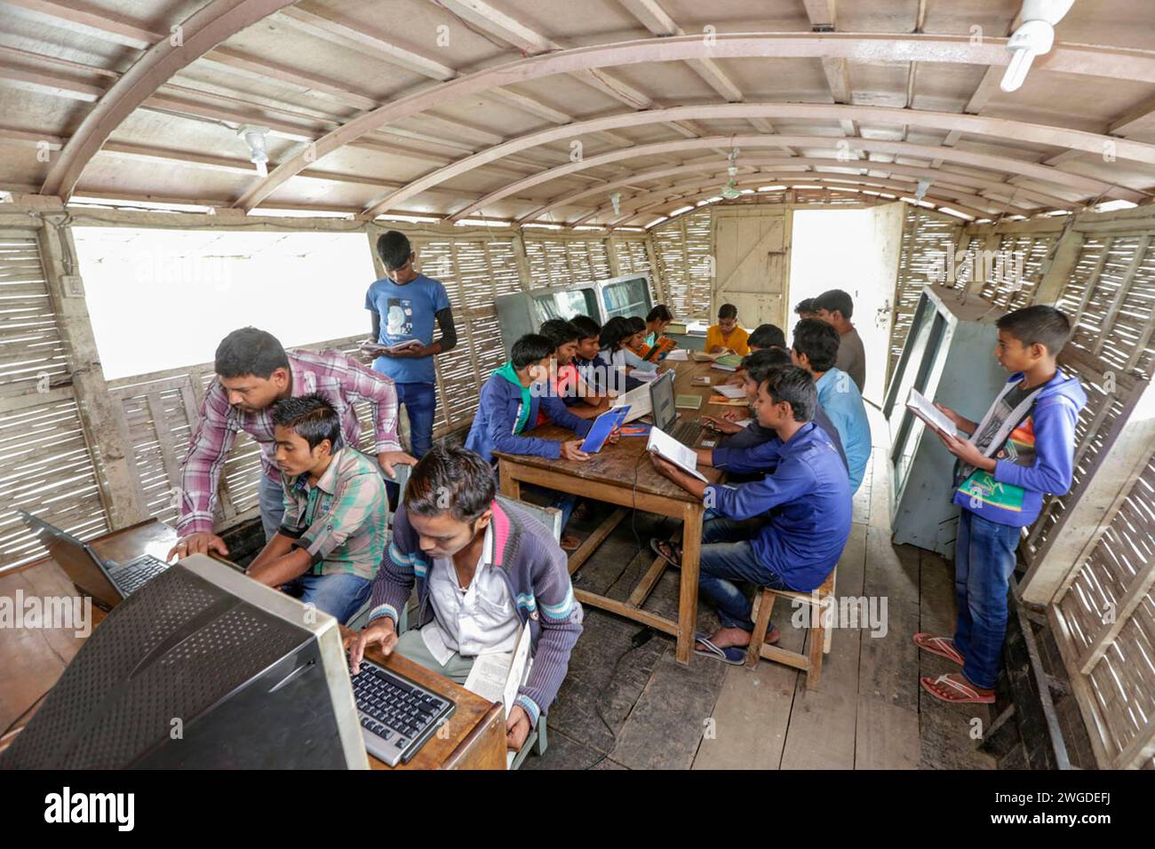Les élèves utilisent l'ordinateur et lisent des livres à la bibliothèque sur une école de bateau à Poundry, Kolom. Le pays a été inondé à deux reprises en 2007 et 332 écoles ont été détruites et 4 893 écoles ont été endommagées. Shidhulai exploite une flotte d'écoles flottantes, de bibliothèques, de cliniques de santé, d'ateliers solaires et de centres de formation flottants avec accès Internet sans fil, desservant près de 97 000 familles dans les régions sujettes aux inondations. Les bateaux eux-mêmes sont équipés de panneaux solaires qui alimentent les ordinateurs, les lumières et le matériel médical. Singra, Natore, Bangladesh. Banque D'Images