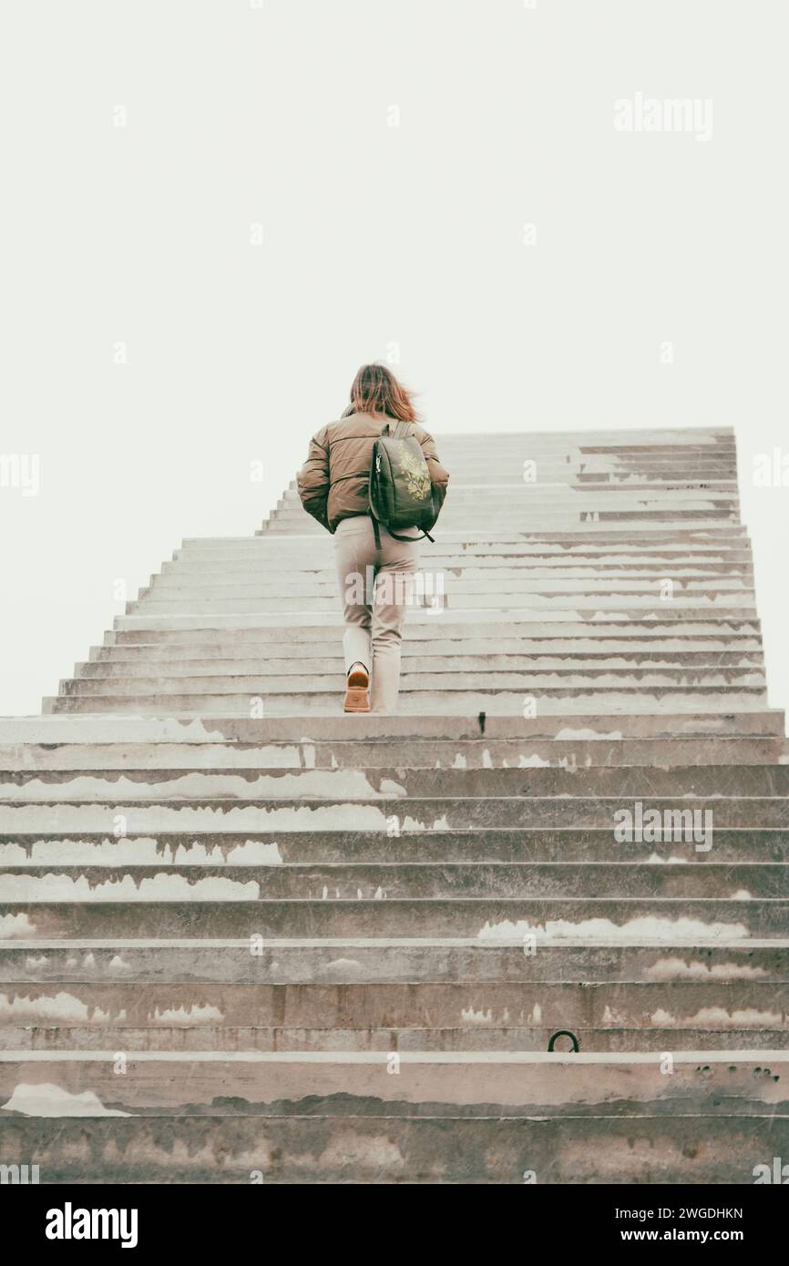 Femme marchant sur les escaliers pour nulle part. Fille grimpant les escaliers. Personne sur le pont inachevé. Escalier vers le ciel. Escaliers vers le succès. Echelle de carrière. Banque D'Images