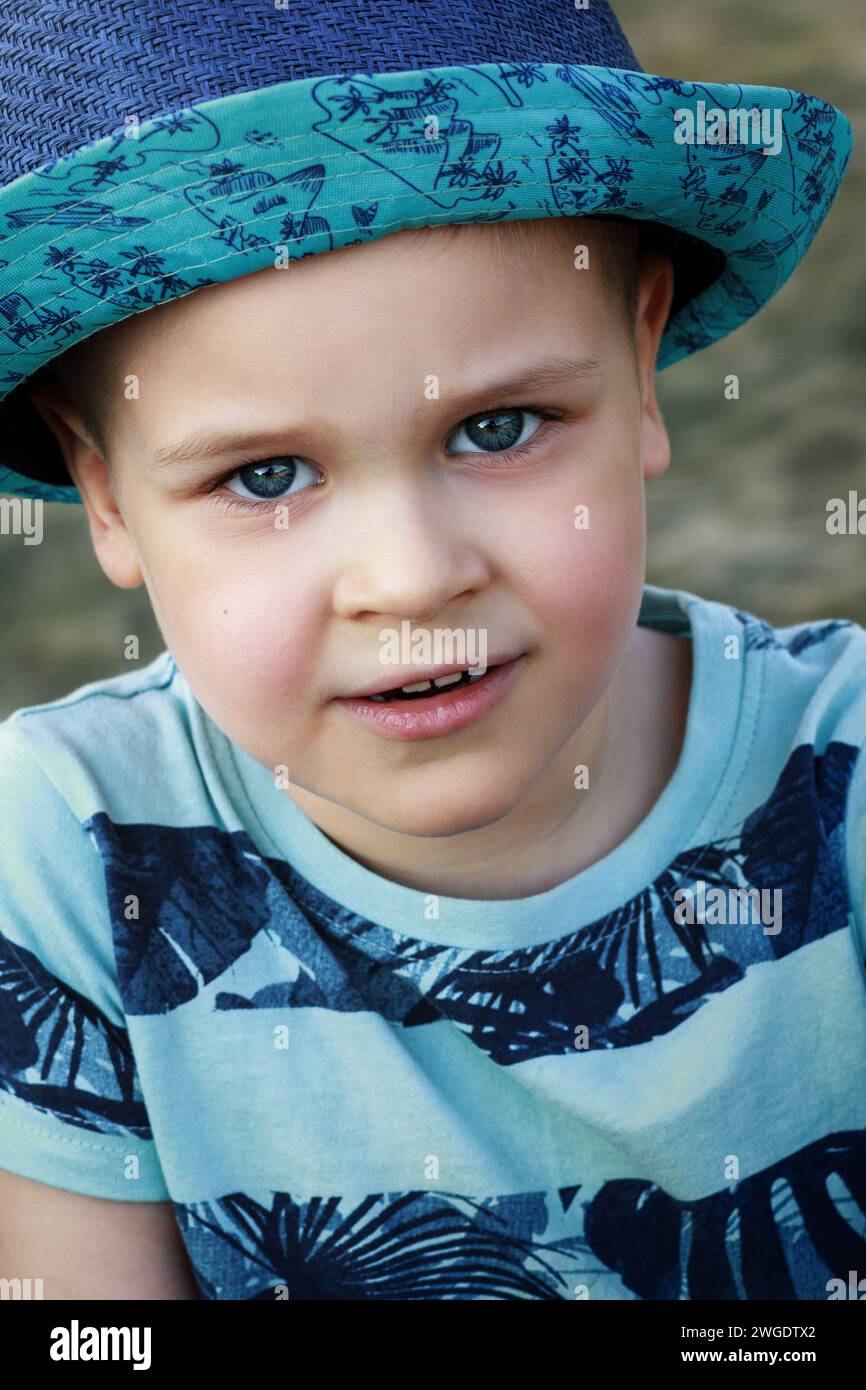 Portrait en gros plan d'un garçon caucasien mignon dans un chapeau bleu et des vêtements bleus. Banque D'Images