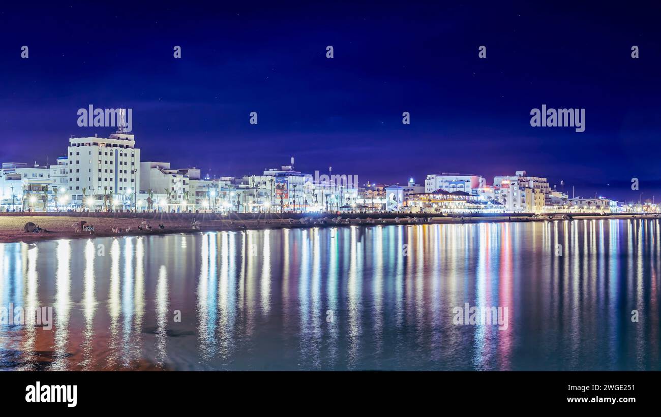 Un paysage urbain avec plage illuminée et eau chatoyante à Mdiq, Maroc Banque D'Images