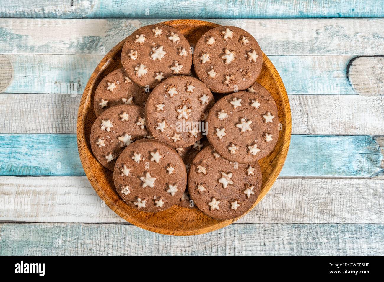 Délicieux biscuits au cacao sucré biscuits sur une assiette en bois. Prise de vue aérienne. Fond bleu coloré. Banque D'Images