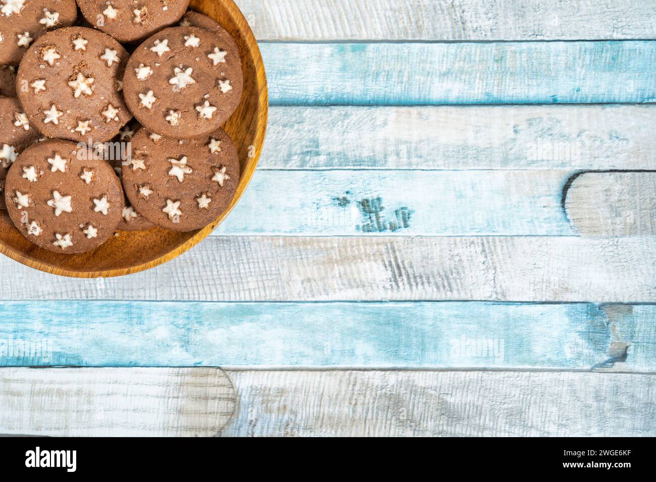 Délicieux biscuits au cacao sucré biscuits sur une assiette en bois. Prise de vue aérienne. Fond bleu coloré. Banque D'Images